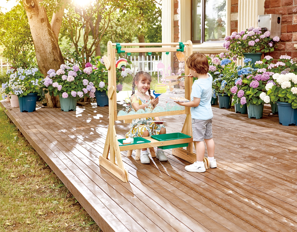Two children happily create art outside using the Nature's Wonders Stamps, making the most of sunny garden play.